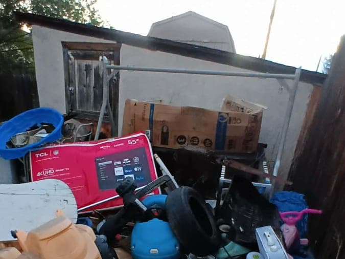 Before: a backyard beside a stucco shed piled with old toys, a TV box, tires and boxes