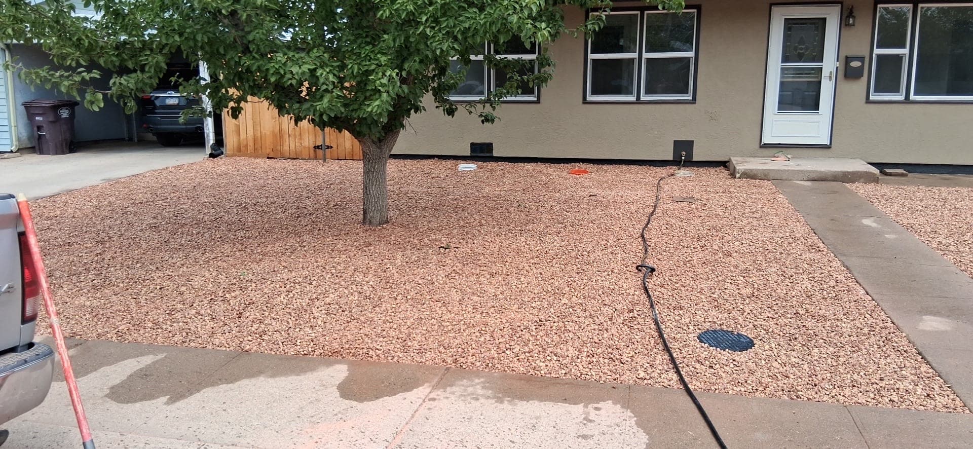 After: the same Pueblo front yard finished in red decorative rock around the tree and walkway