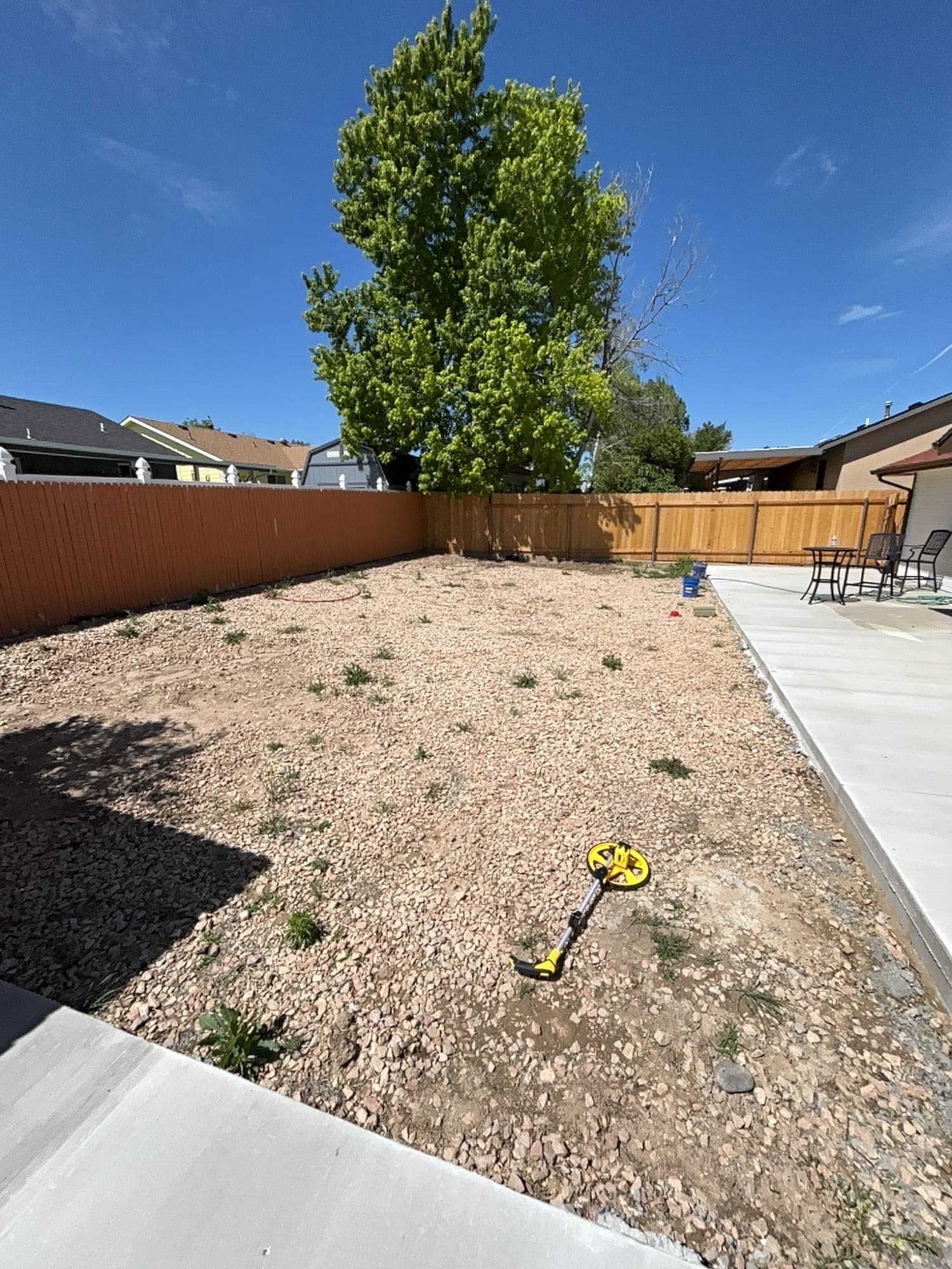 Before: a Pueblo backyard of bare dirt, weeds and gravel with a measuring wheel on the ground