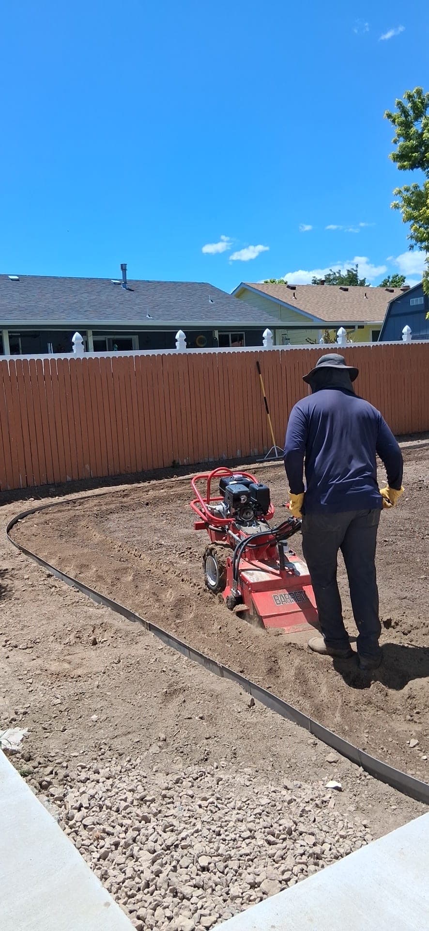 Crew member tilling a Pueblo backyard with a walk-behind tiller before new sod goes in, new steel edging in place